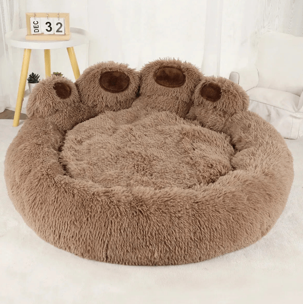 Round brown pet bed with paw-shaped ends on a white surface.